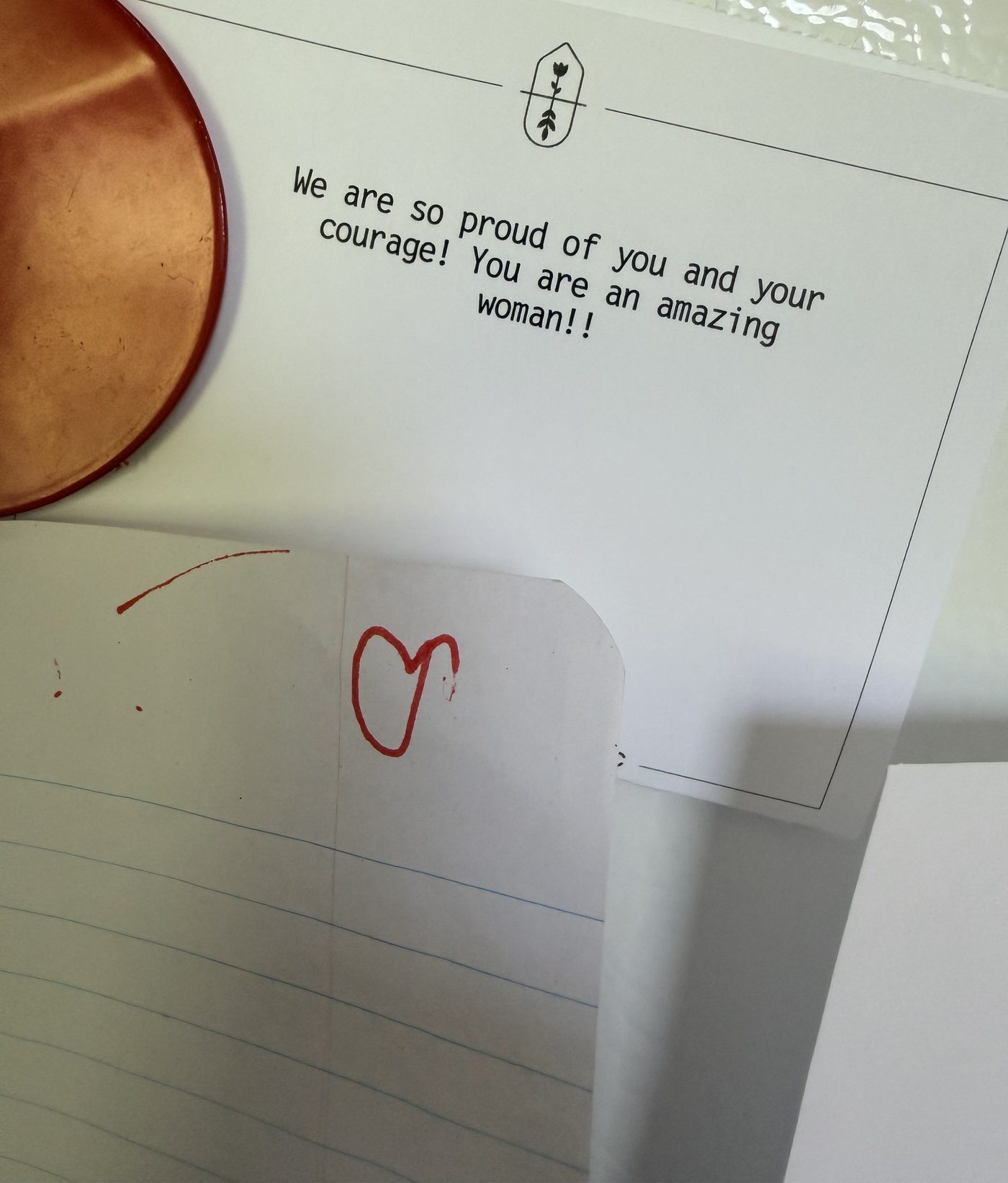 A handwritten note reading "We are so proud of you and your courage! You are an amazing woman!!" with a small red heart drawn beneath it.