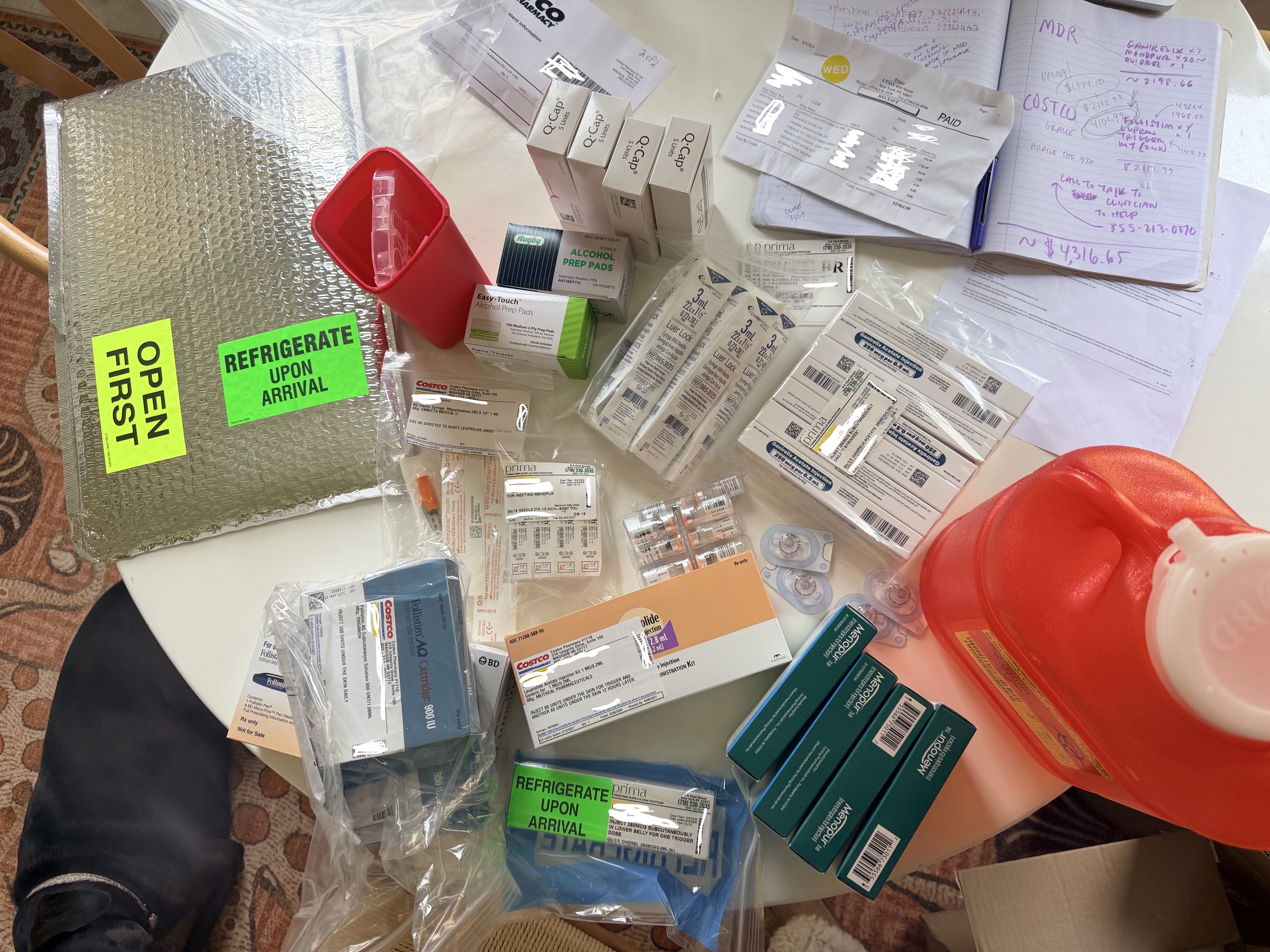 All egg freezing medications and supplies spread out on counter — Follistim pen, Menopur vials, syringes, sharps container, mixing supplies